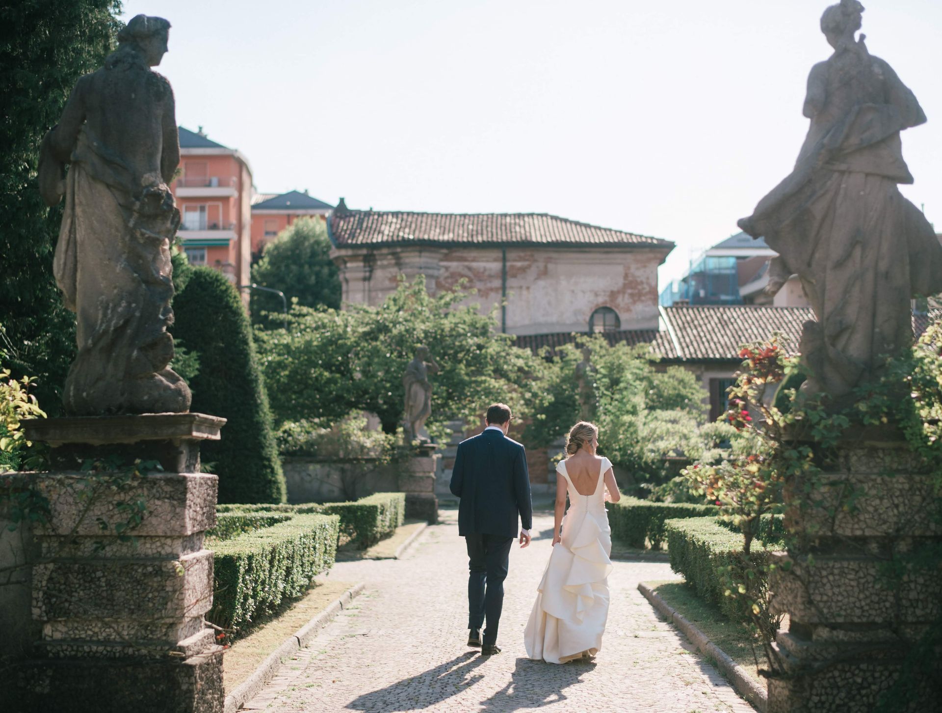 Una sposa e uno sposo stanno camminando lungo un sentiero con statue sullo sfondo
