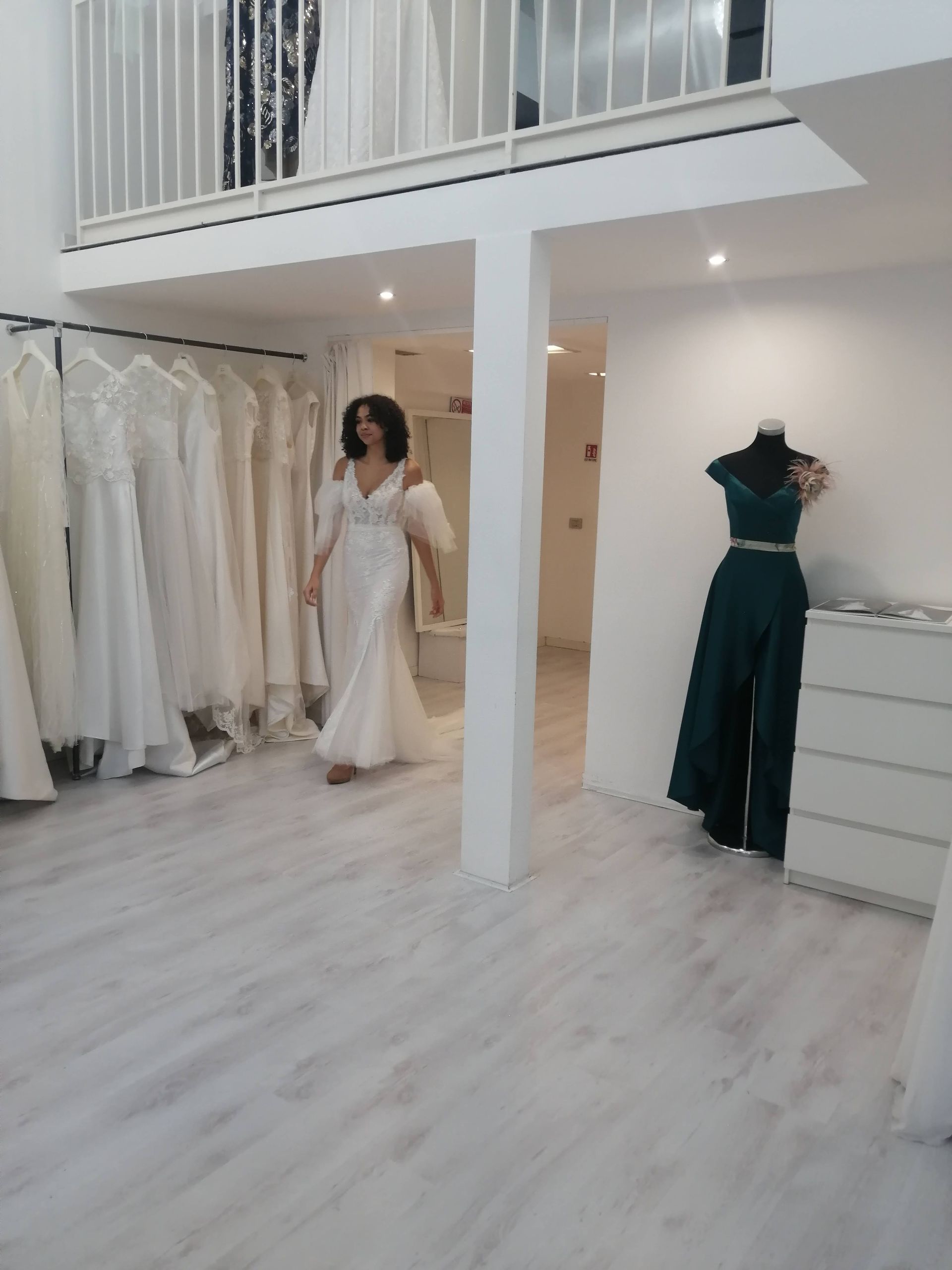 Una donna in abito bianco è in piedi in un negozio di abiti da sposa