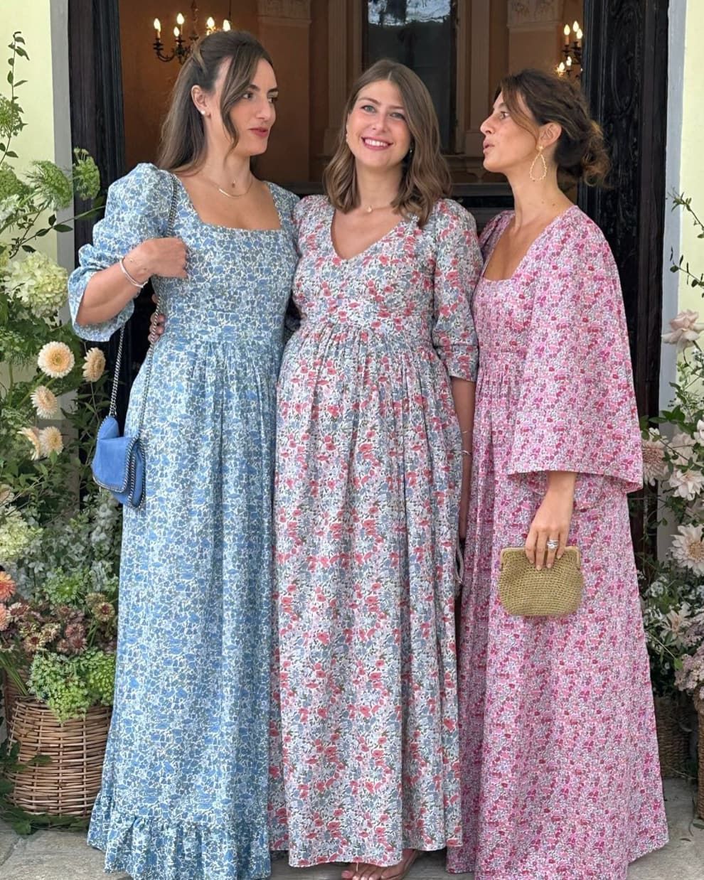 Tre donne in abiti floreali posano per una foto.