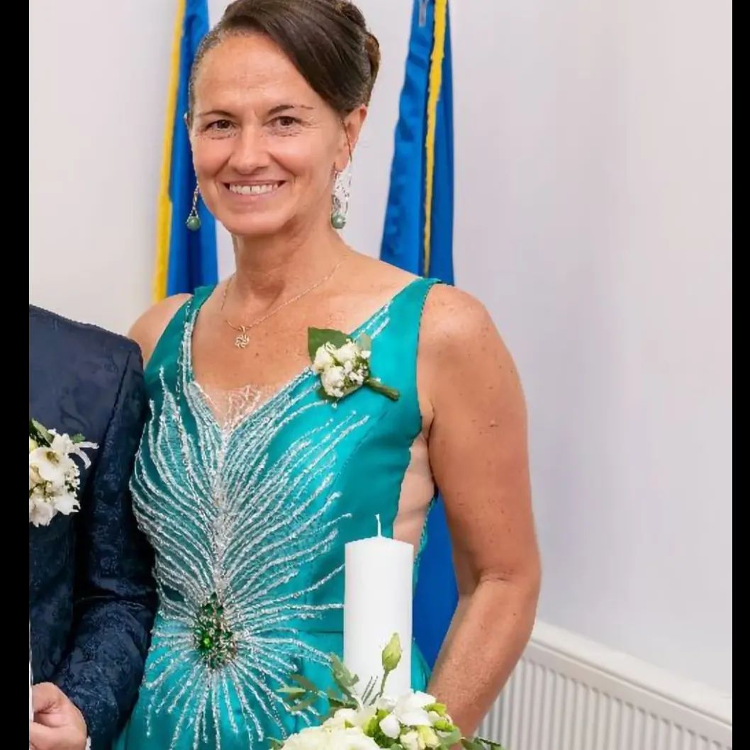 Una donna in un vestito blu tiene in mano una candela bianca