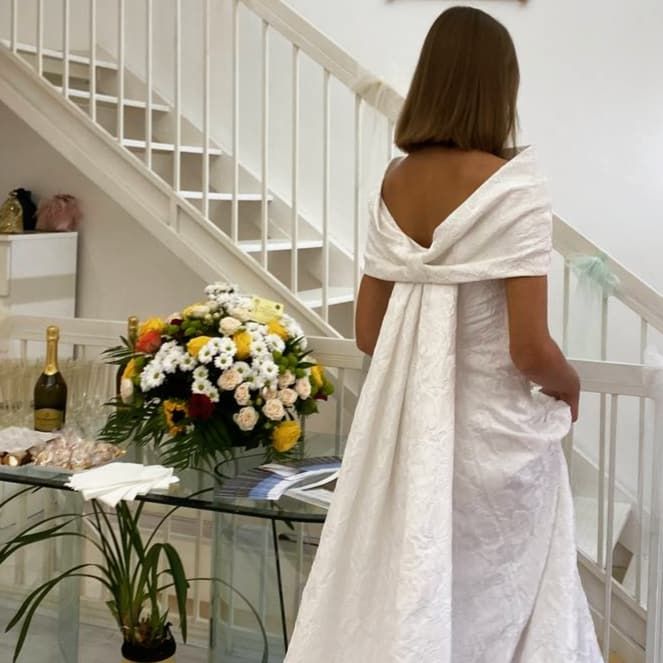 Una donna in abito bianco è in piedi davanti alle scale