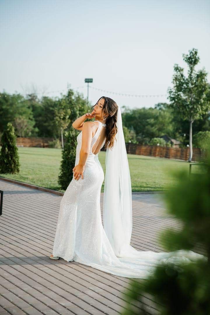 Una donna in abito da sposa e velo è in piedi su un ponte di legno.