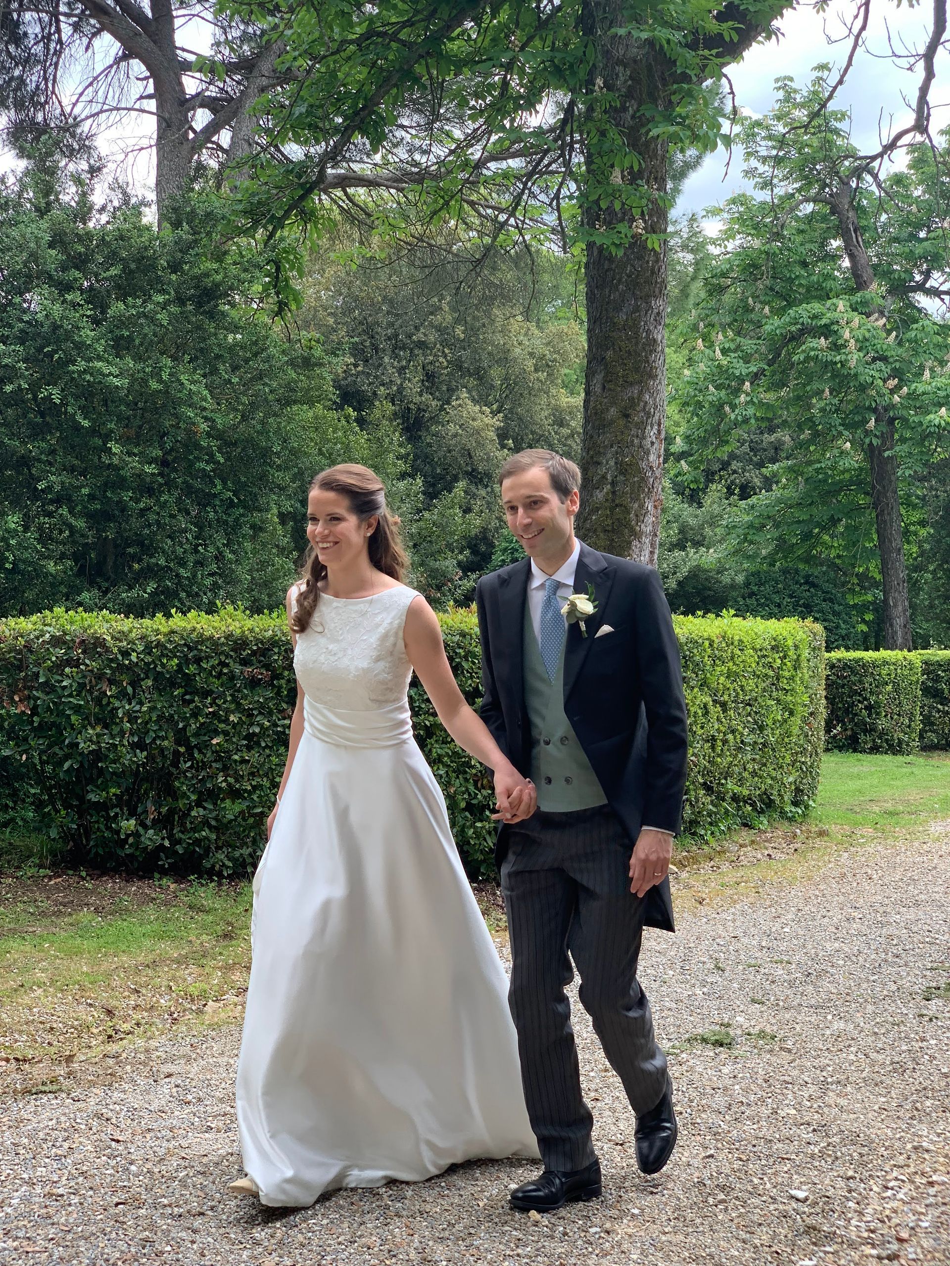 Una coppia di sposi cammina lungo una strada sterrata tenendosi per mano.