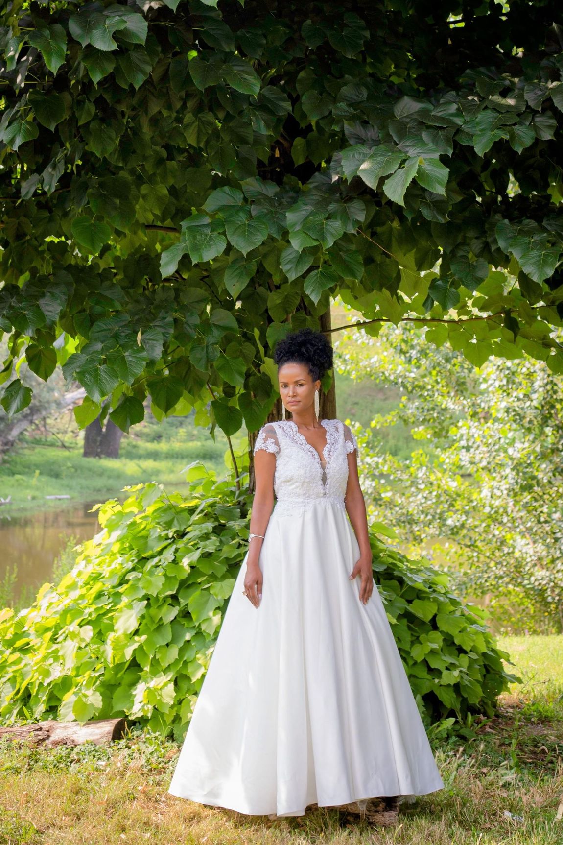 Una donna vestita di bianco è in piedi sotto un albero.