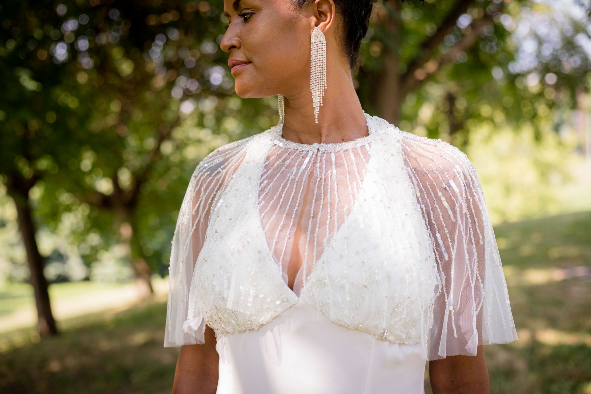 Una donna vestita di bianco è in piedi in un parco.