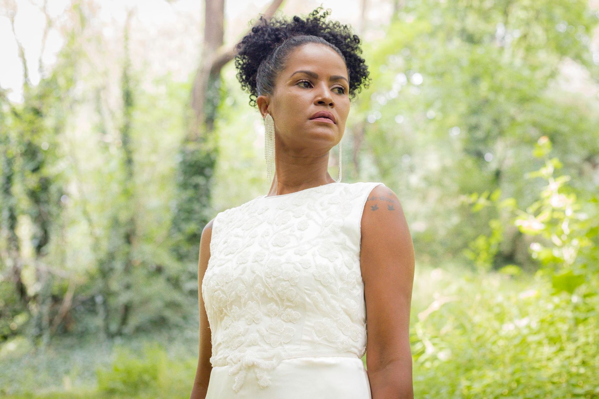 Una donna vestita di bianco è in piedi nel bosco.