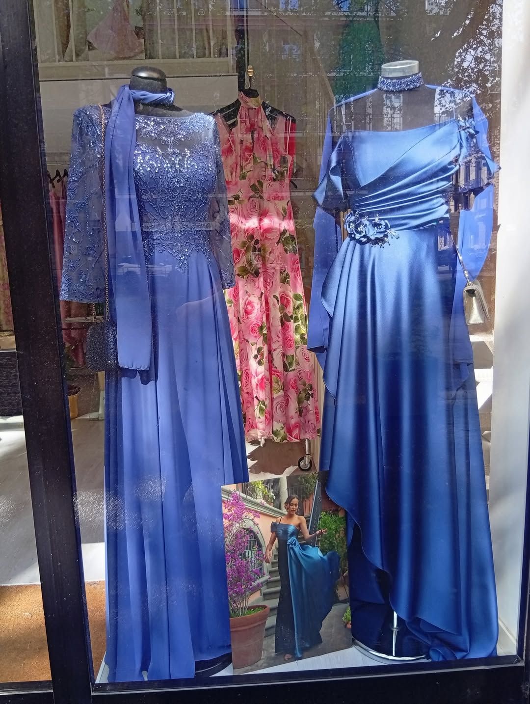 Due abiti blu sono esposti nella vetrina di un negozio.