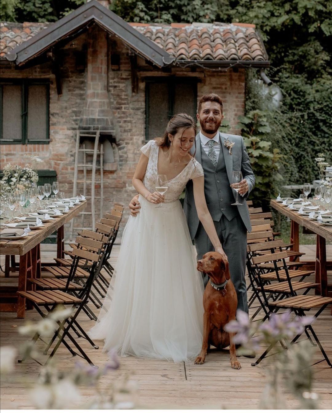Una coppia di sposi è in piedi accanto a un cane durante il ricevimento di nozze.