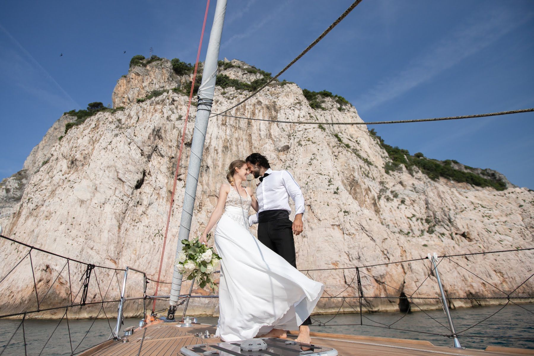Una sposa e uno sposo si baciano su una barca di fronte a una montagna.