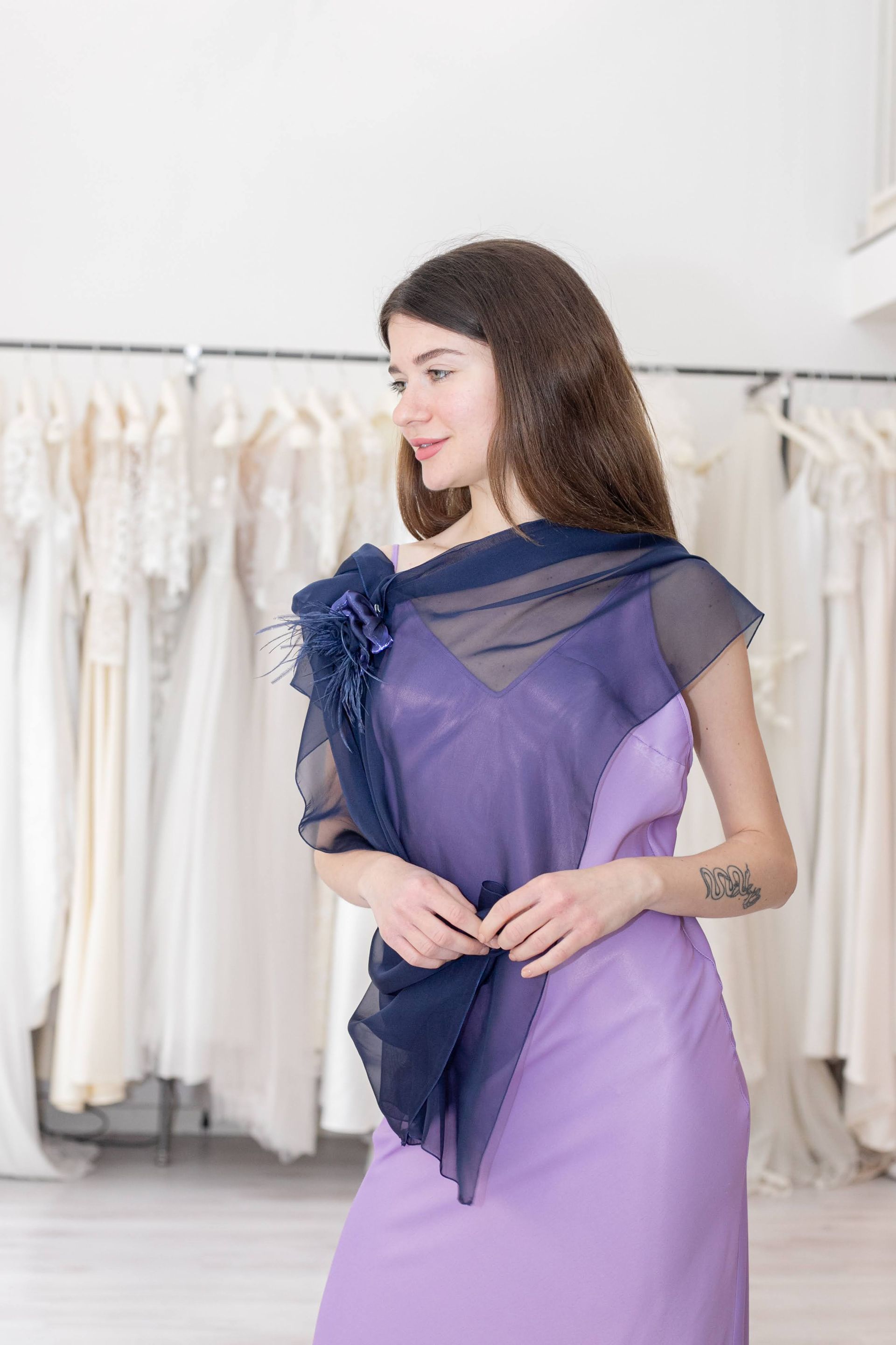 Una donna indossa un vestito viola e una sciarpa blu.