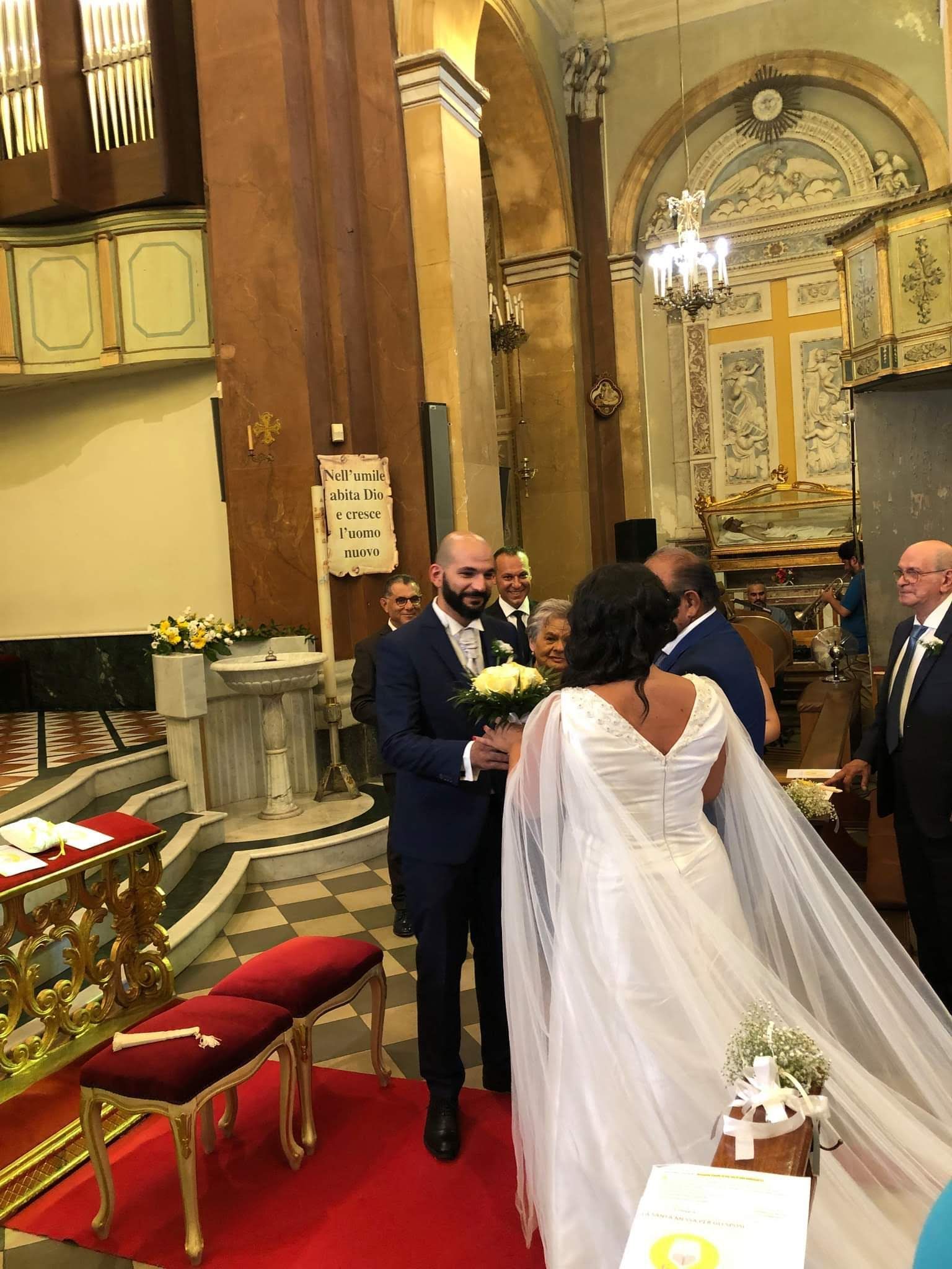 Una sposa e uno sposo stanno camminando lungo la navata di una chiesa.