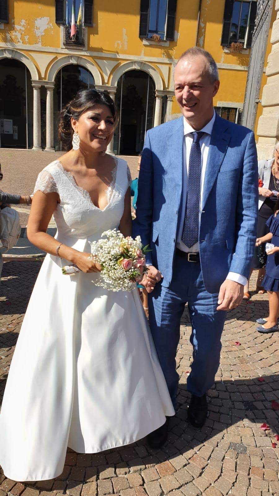 Una coppia di sposi posa per una foto davanti a un edificio giallo.