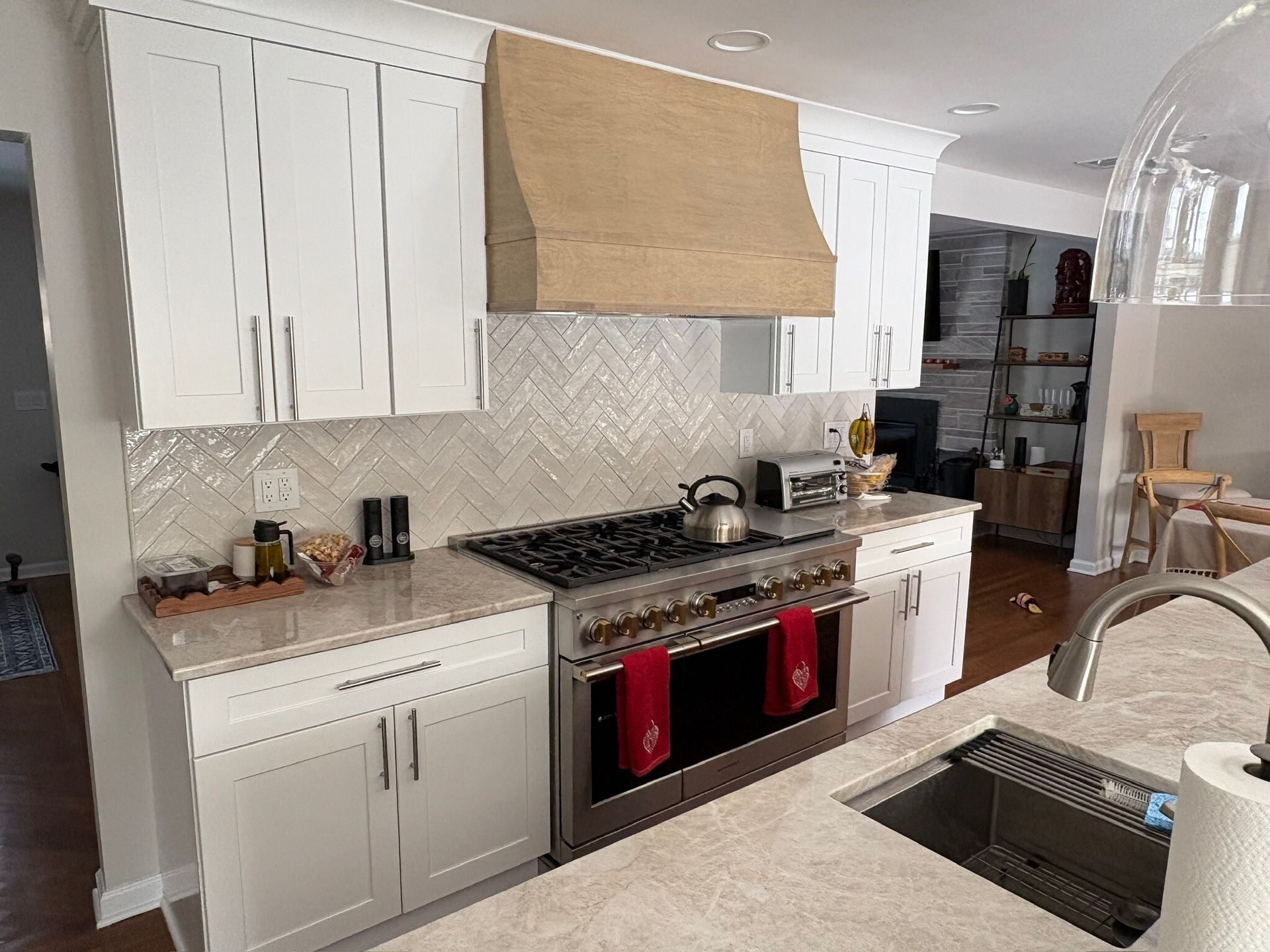 Bright kitchen with white cabinets, beige range hood, gas stove, and stainless sink in foreground.