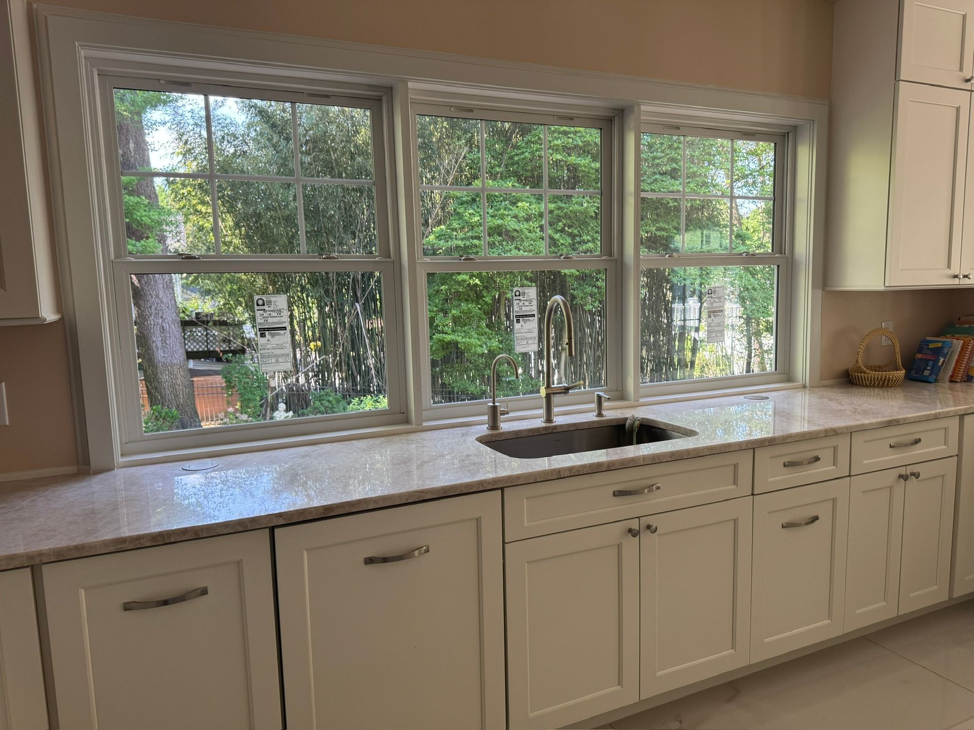 Kitchen counter with double sink beneath large windows overlooking trees