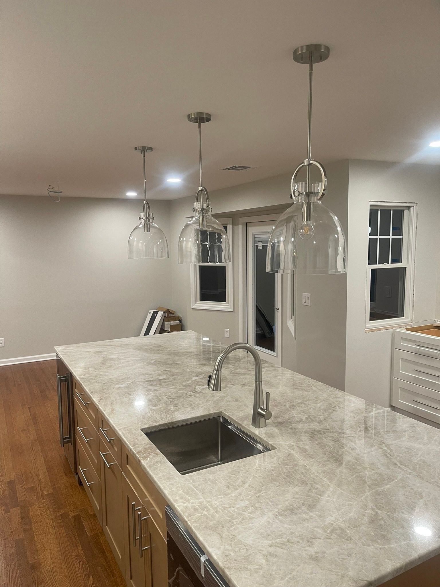 Modern kitchen with large island, granite countertop, pendant lights, and stainless sink.