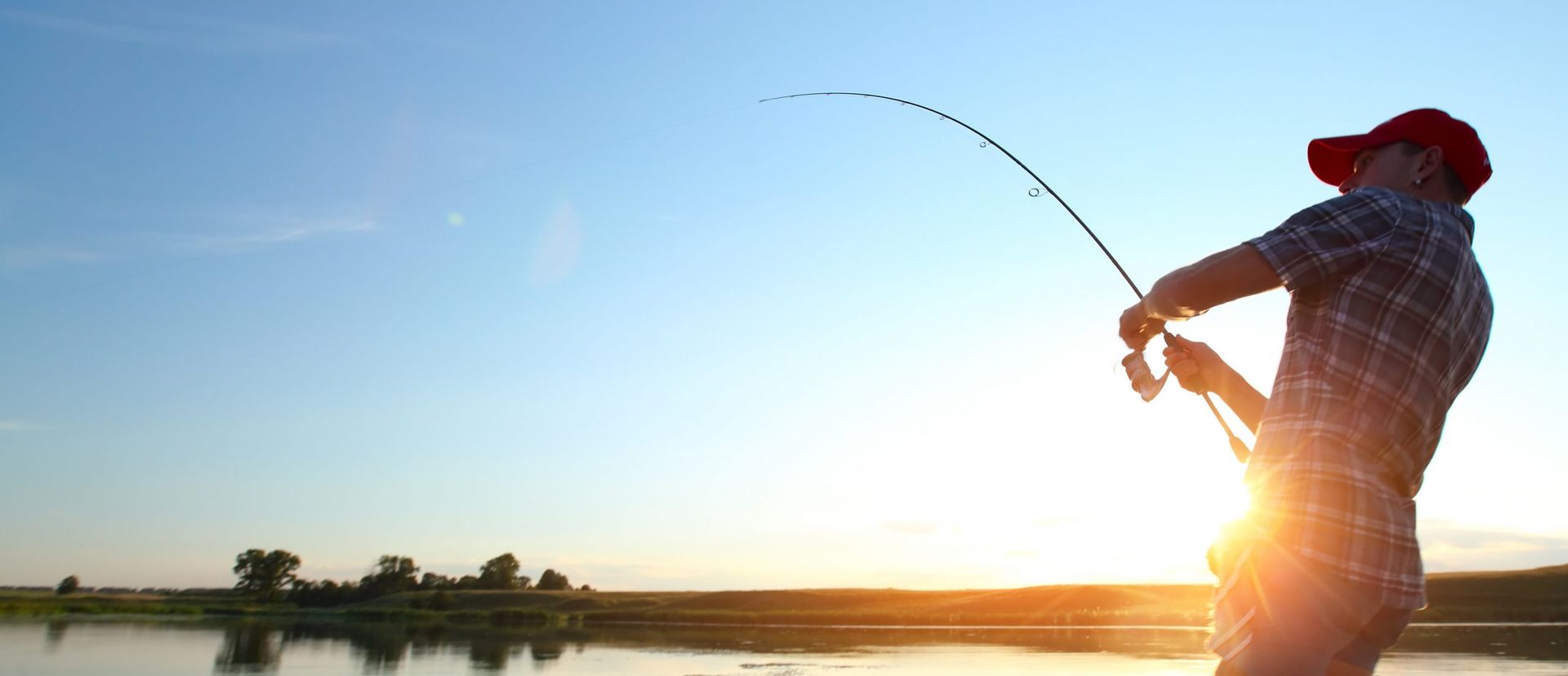 A man in a red hat is fishing on a lake
