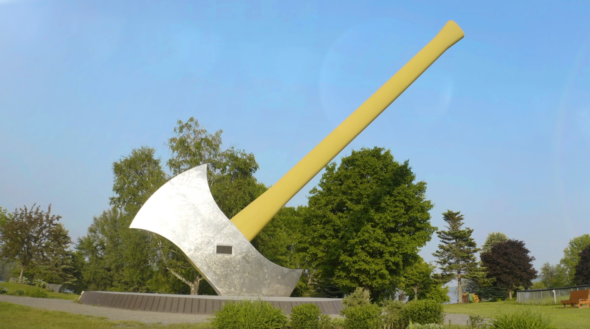 Giant axe monument with a silver blade and yellow handle, outdoors.