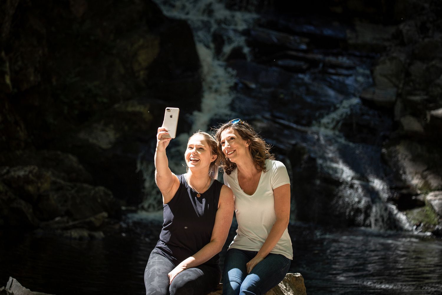 Two women taking a selfie in front of a waterfall.
