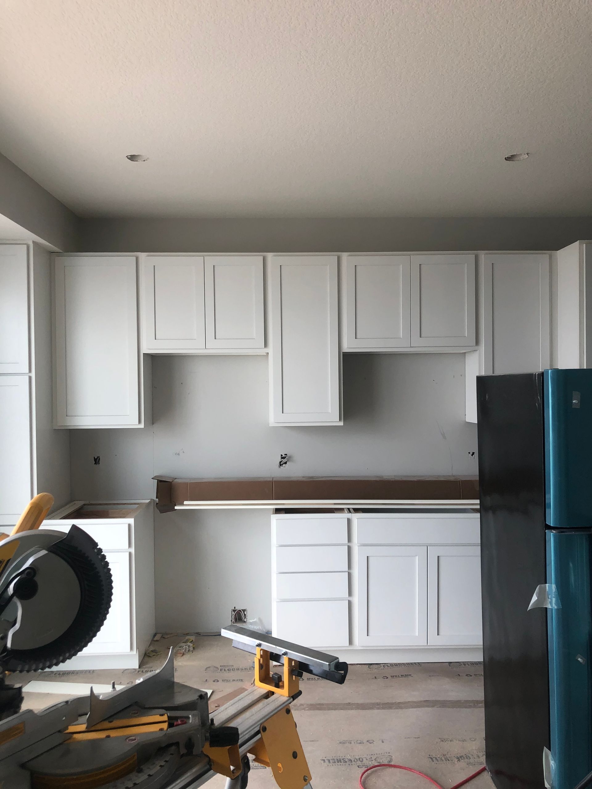 A kitchen with white cabinets and a black refrigerator