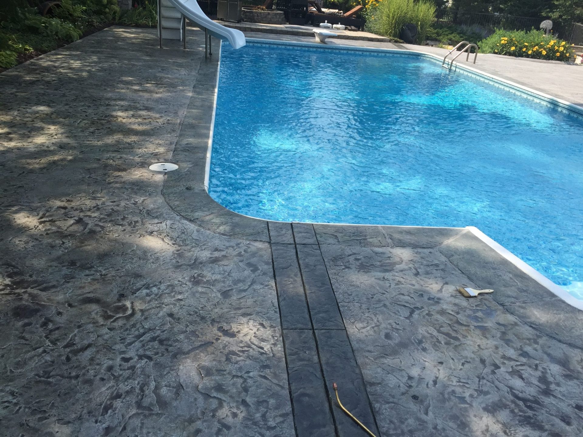 Backyard swimming pool with bright blue water and a stone deck