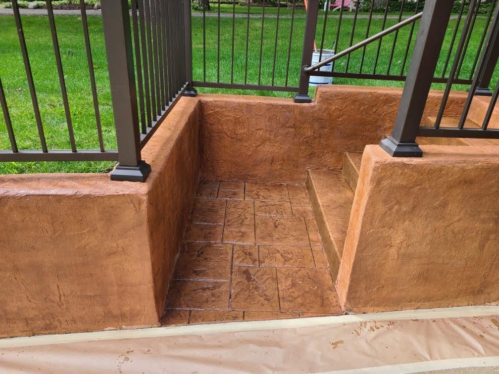 Concrete ramp between black railings leading to a grassy area and steps.