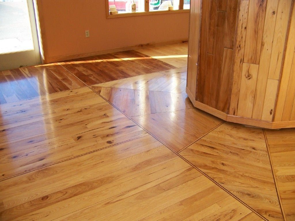 Sunlit wooden floor with a curved wood wall and reflections in an empty room