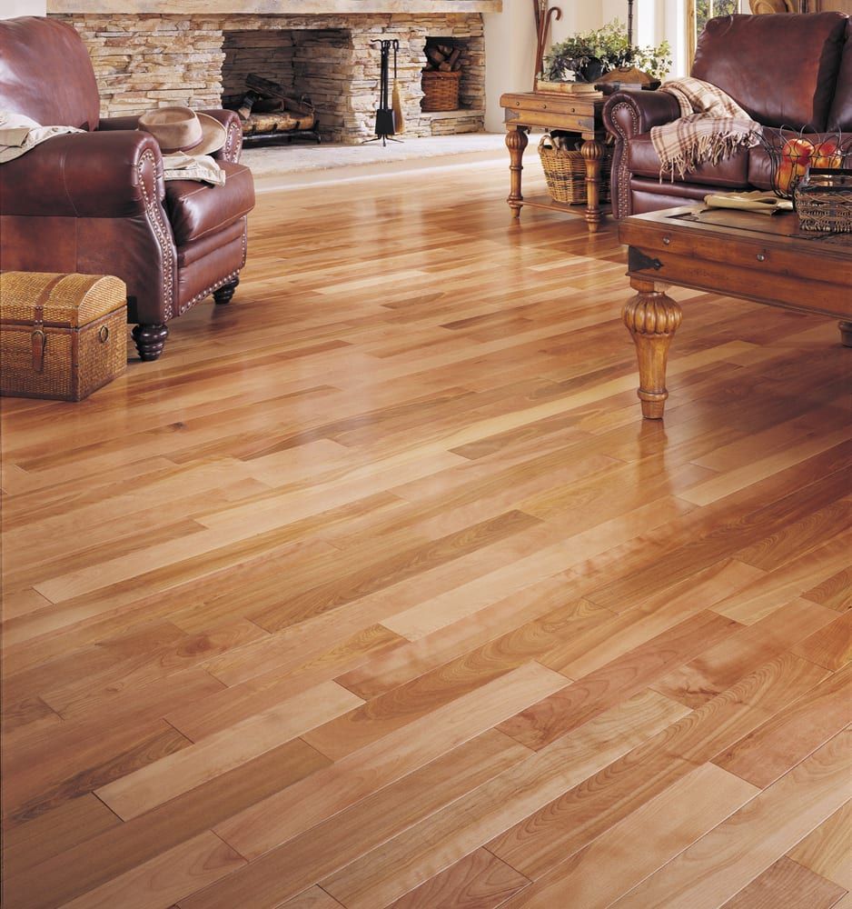 Bright hardwood living room floor with leather chairs, stone fireplace, and wooden coffee table
