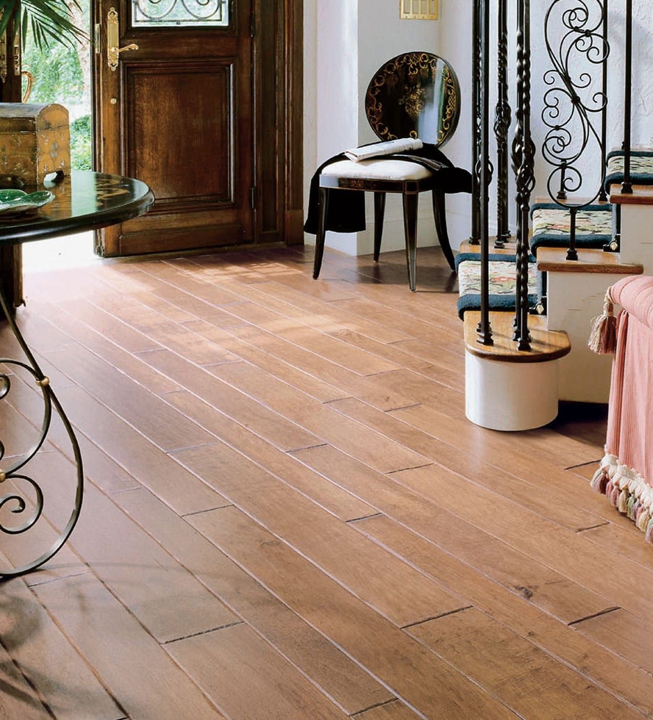 Elegant room with light wood floor, ornate chairs, and a round mirror by a door