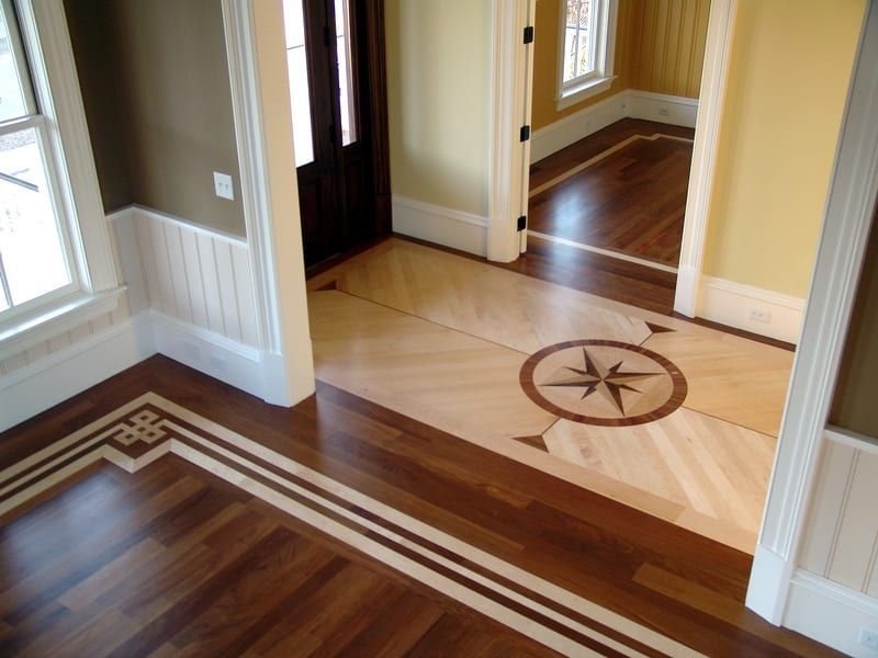 Hallway with polished wood and cream tile floors, white trim, and a compass inlay