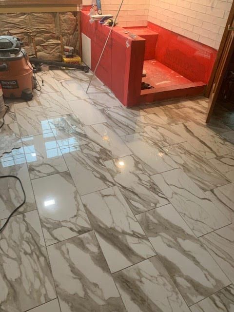 Small room with glossy marble-pattern tile floor and a red built-in bench or seat against a white brick wall.