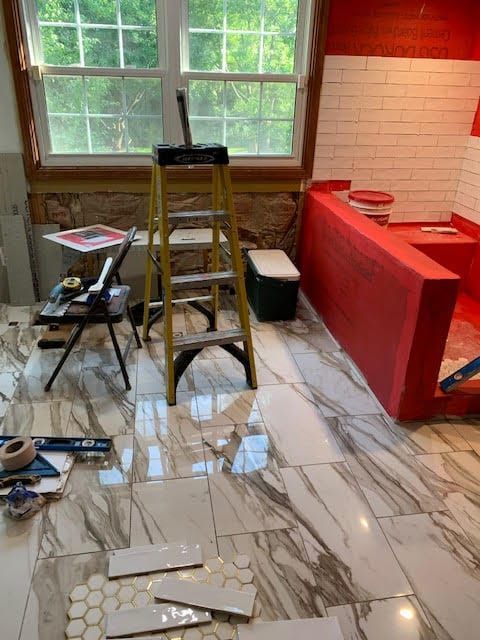 Kitchen under renovation with red cabinets, ladder, tools, and a windowed wall.
