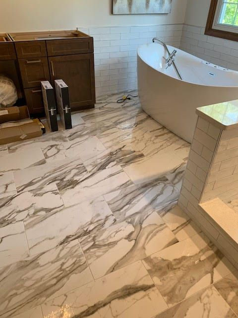 Bathroom with marble floor, white freestanding tub, and wooden vanity cabinet.