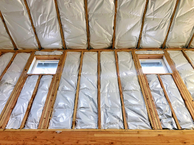 The ceiling of a building with a lot of insulation and windows.
