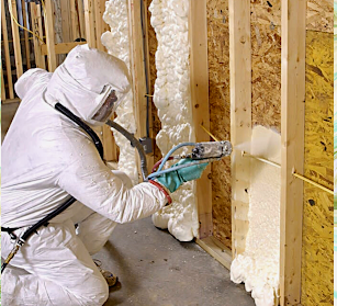 A man is spraying foam on a wooden wall
