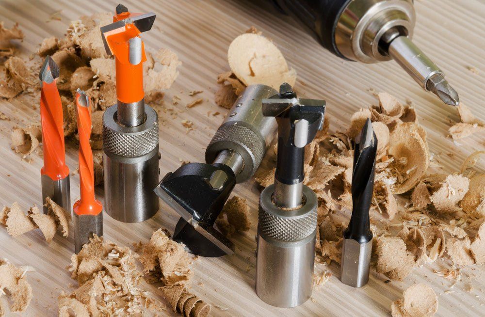 Machine Tool Cutters And Drill Bits In The Sawdust On Wood Background — Express Timber Solutions In Long Jetty NSW