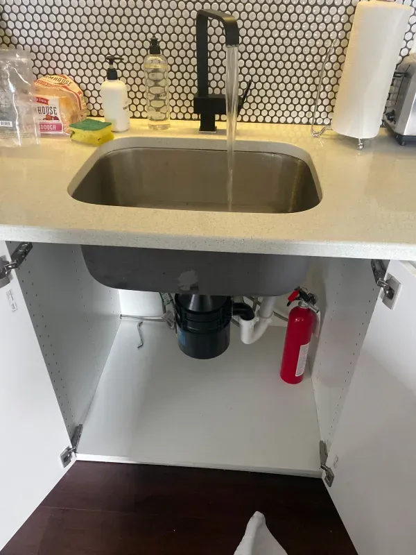 A kitchen sink with a fire extinguisher underneath it