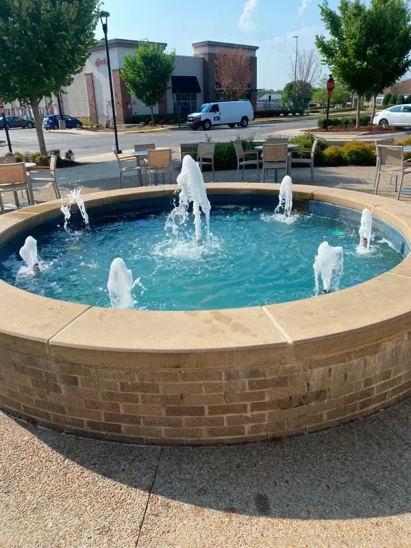 A fountain is surrounded by chairs and a brick wall