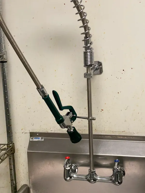 A faucet with a green handle is attached to a sink