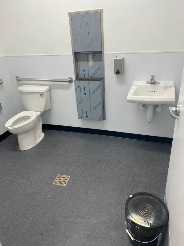 A bathroom with a toilet a sink and a trash can