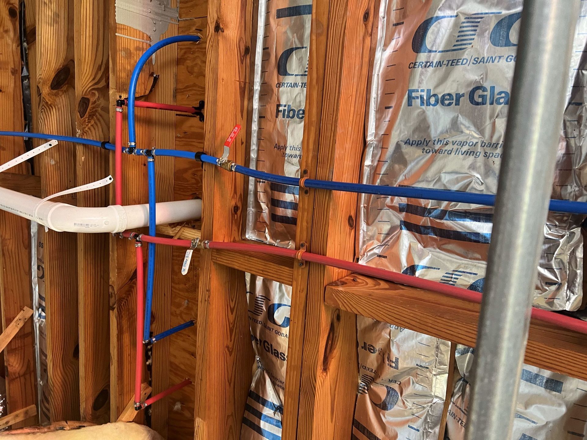 A bathroom with a lot of pipes and aluminum foil on the wall.