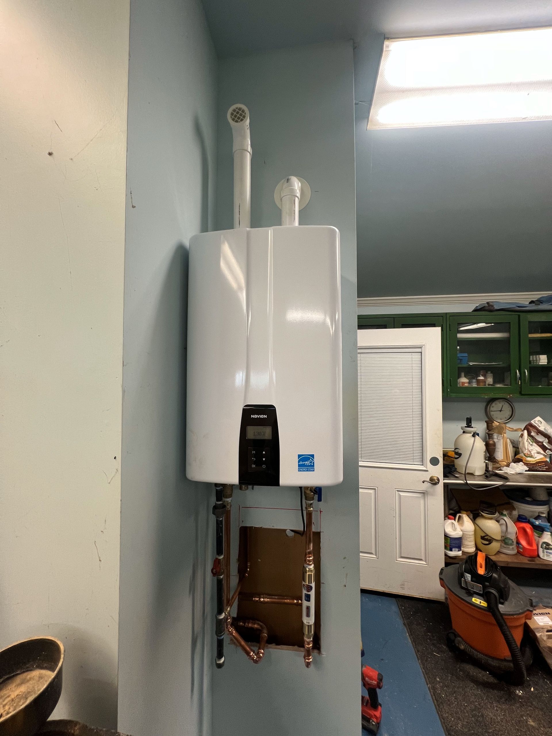 A white water heater is mounted on a wall in a room.