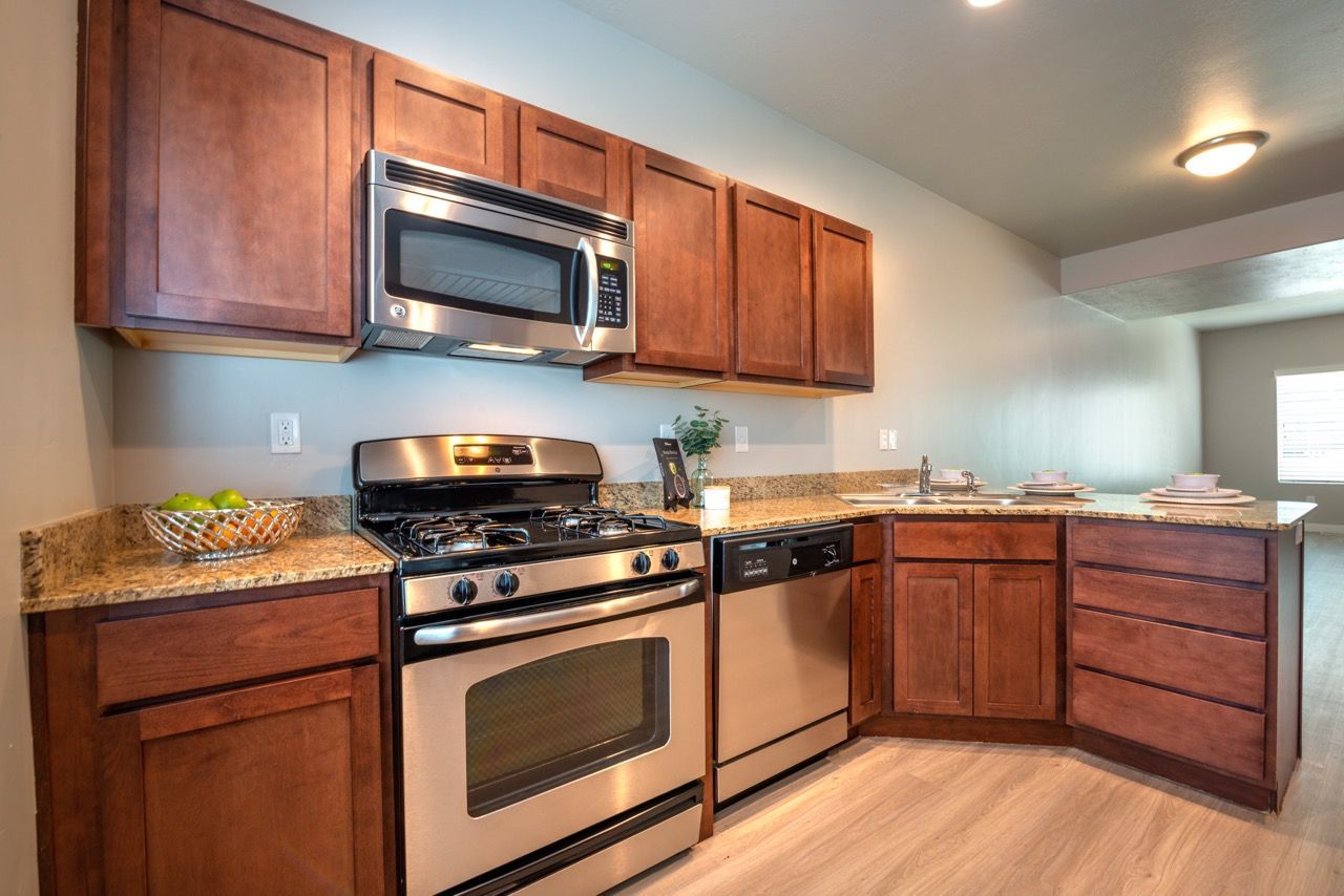 Kitchen in a rental unit with dark wood cabinets, granite countertops, and stainless steel appliances.