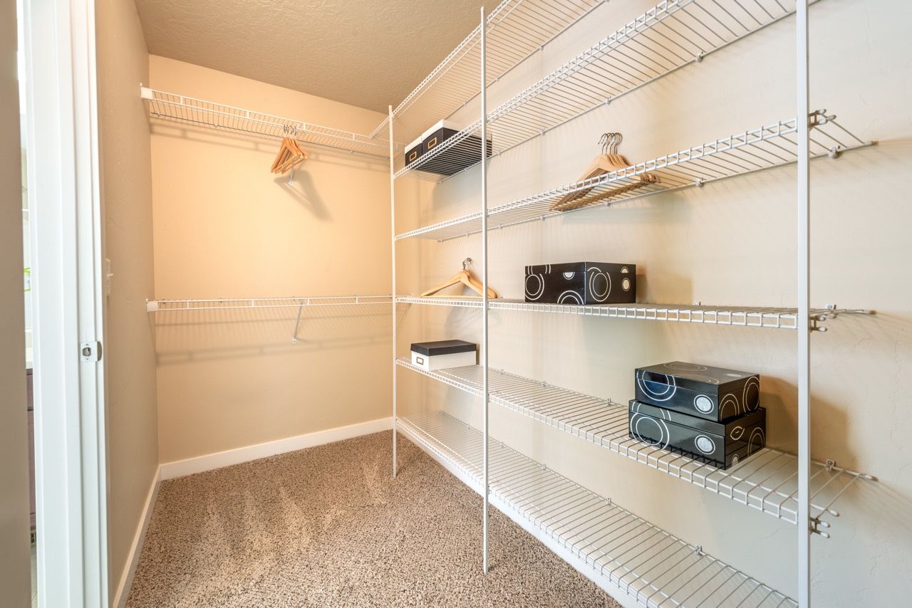 Spacious walk-in closet with white wire shelving and a beige carpet.