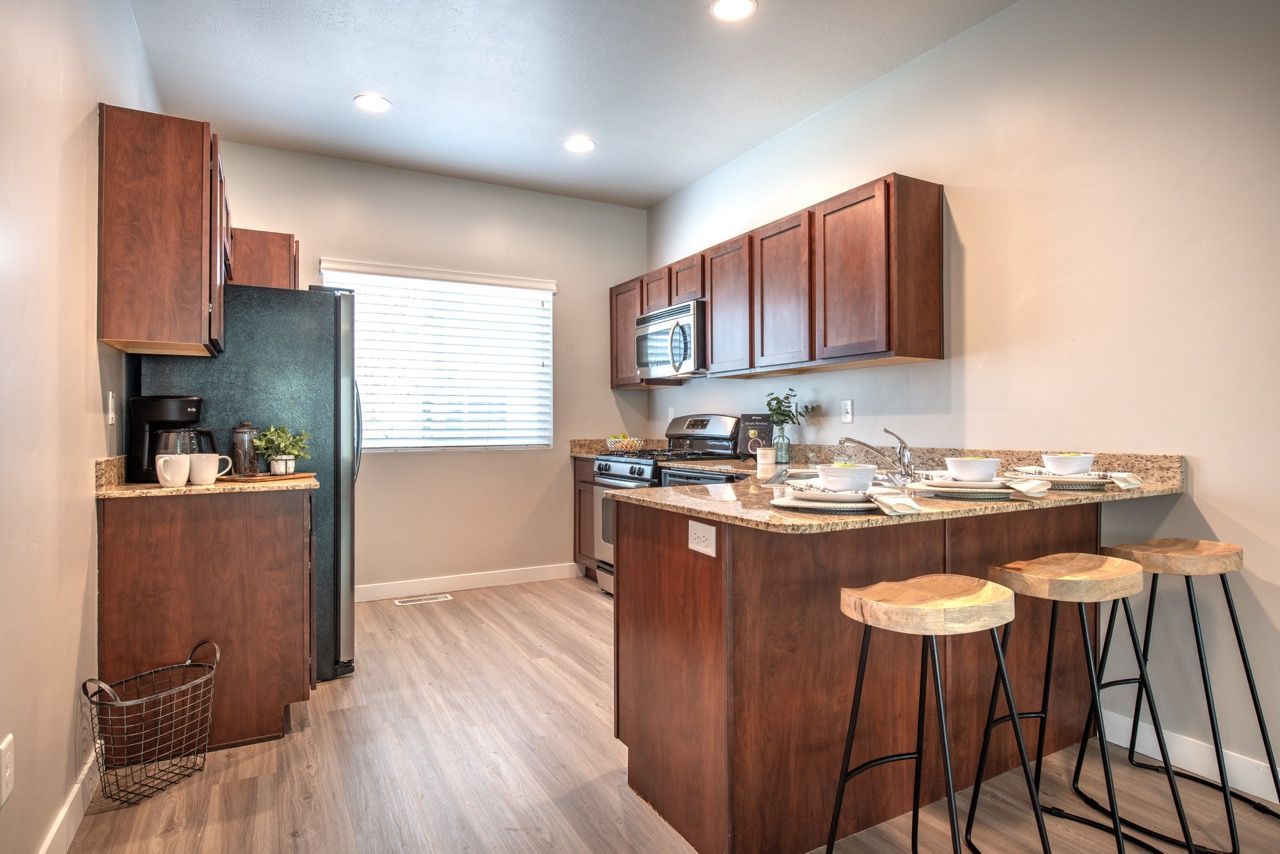 Open-concept kitchen with dark wood cabinets, granite countertops, stainless steel appliances, and a breakfast island with stools.