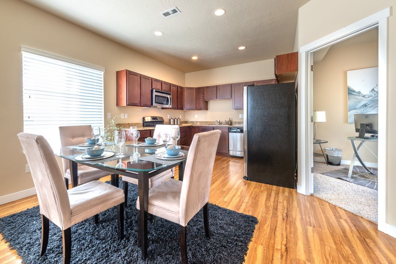 Open-concept kitchen and dining area with glass dining table and beige upholstered chairs.