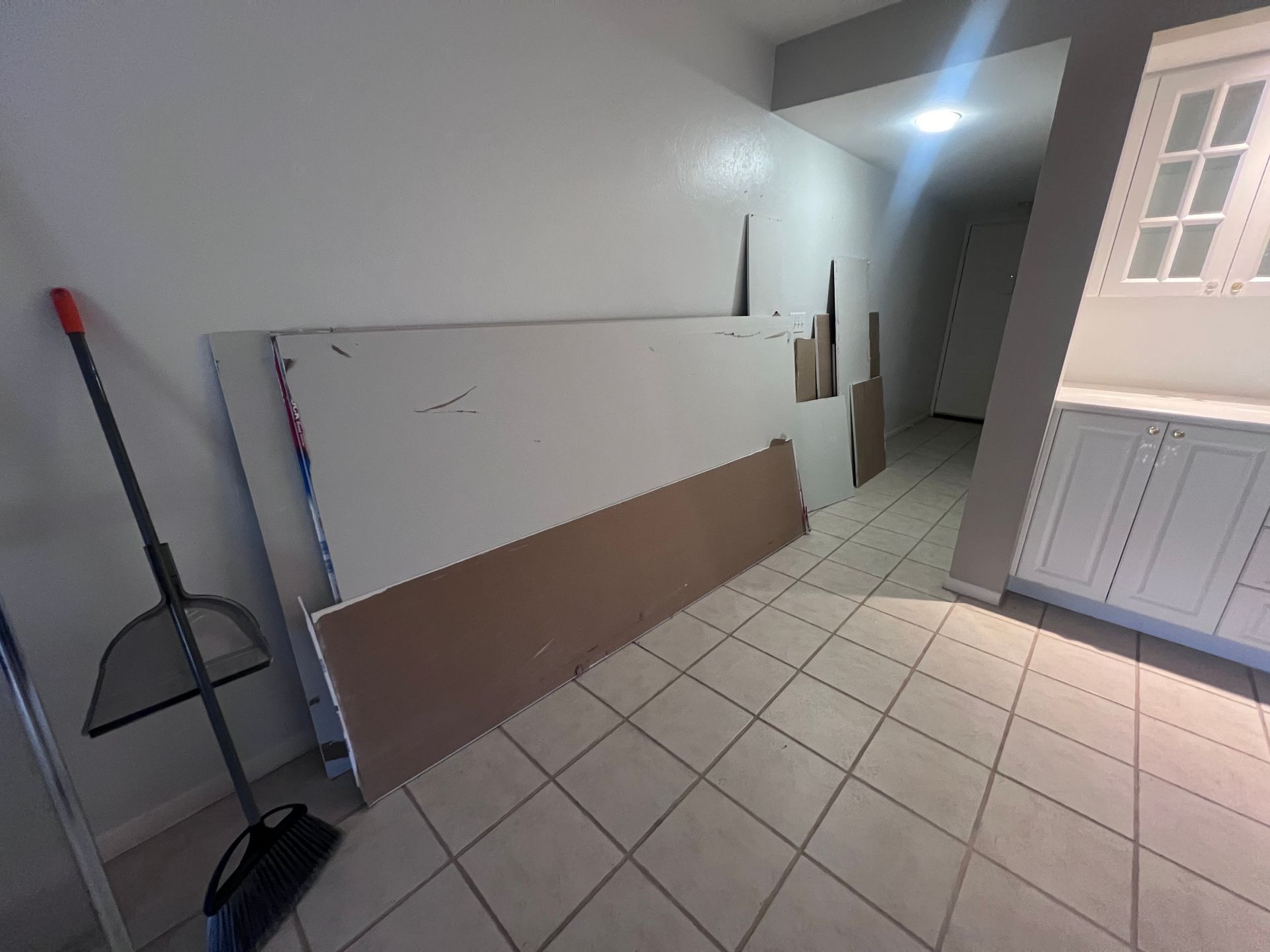 A room with a broom and a stack of boards on the floor