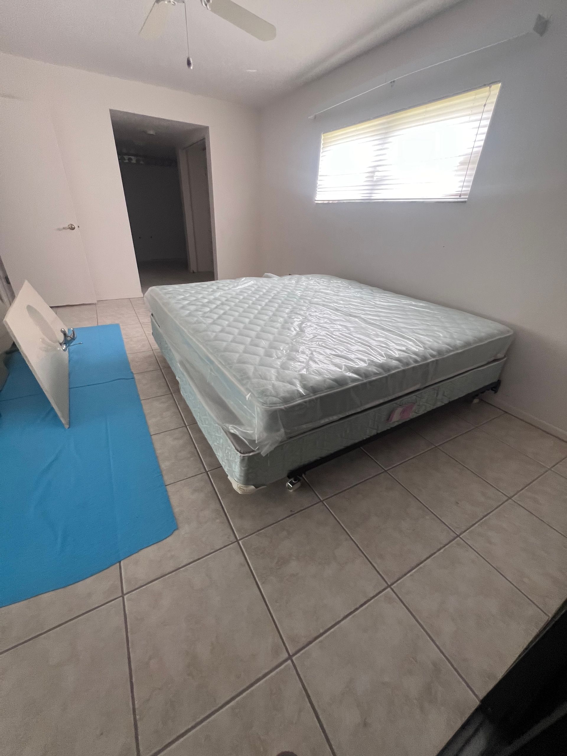 A bedroom with a mattress on the floor and a window.