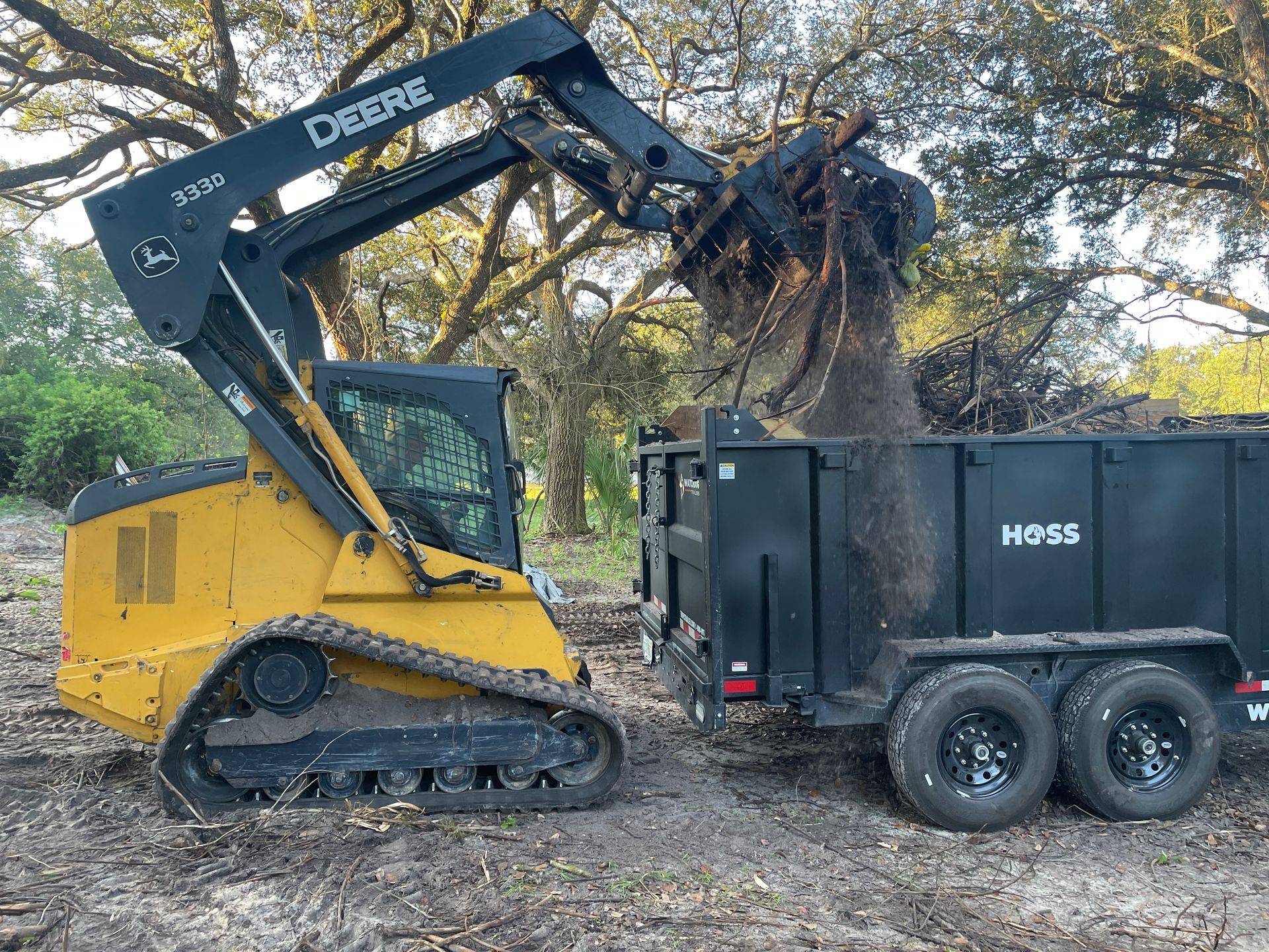 A bulldozer is loading dirt into a dumpster.