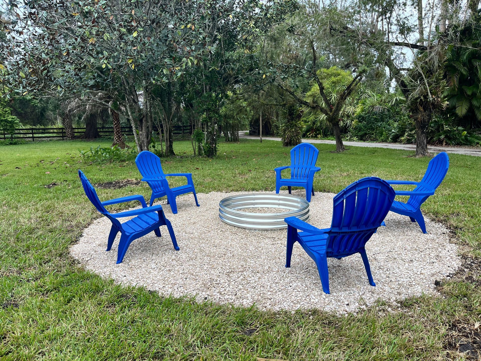 A group of blue chairs are sitting around a fire pit.