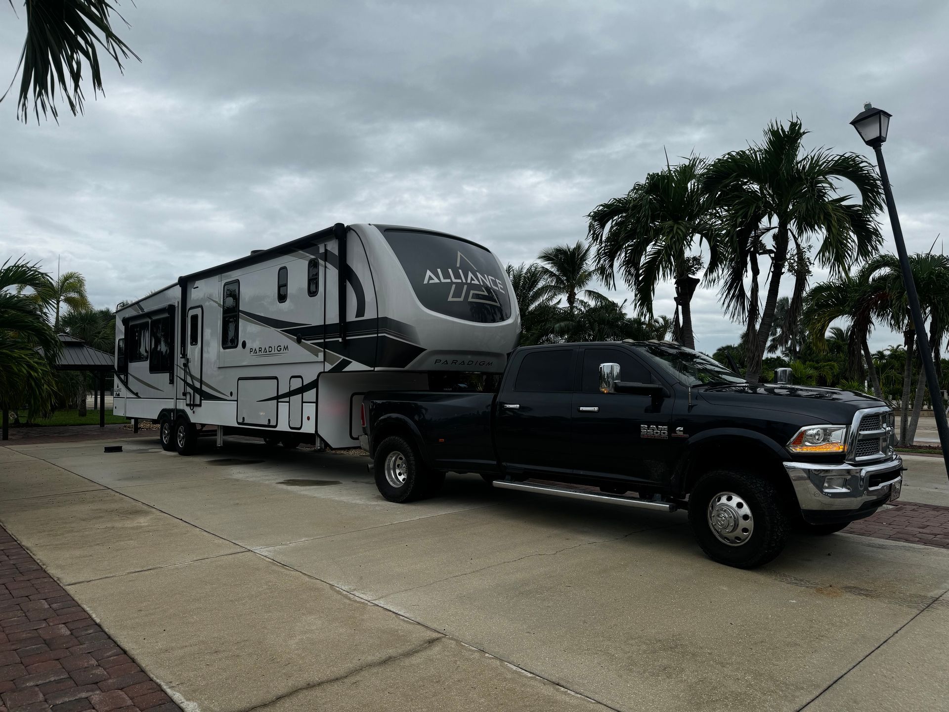 A black truck is towing a trailer in a parking lot.
